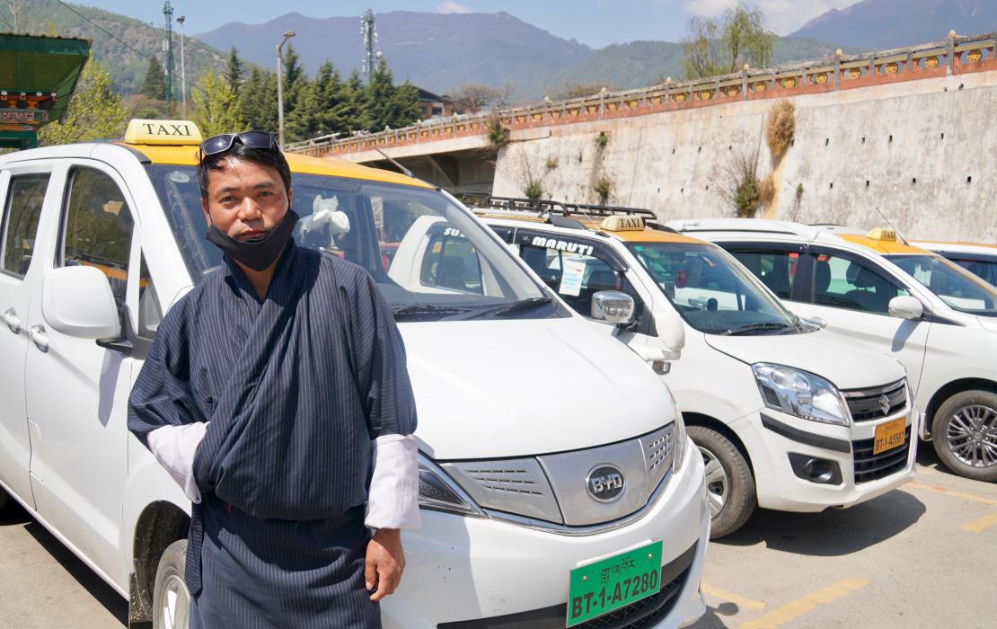 A taxi operator in Bhutan in front of his new EV