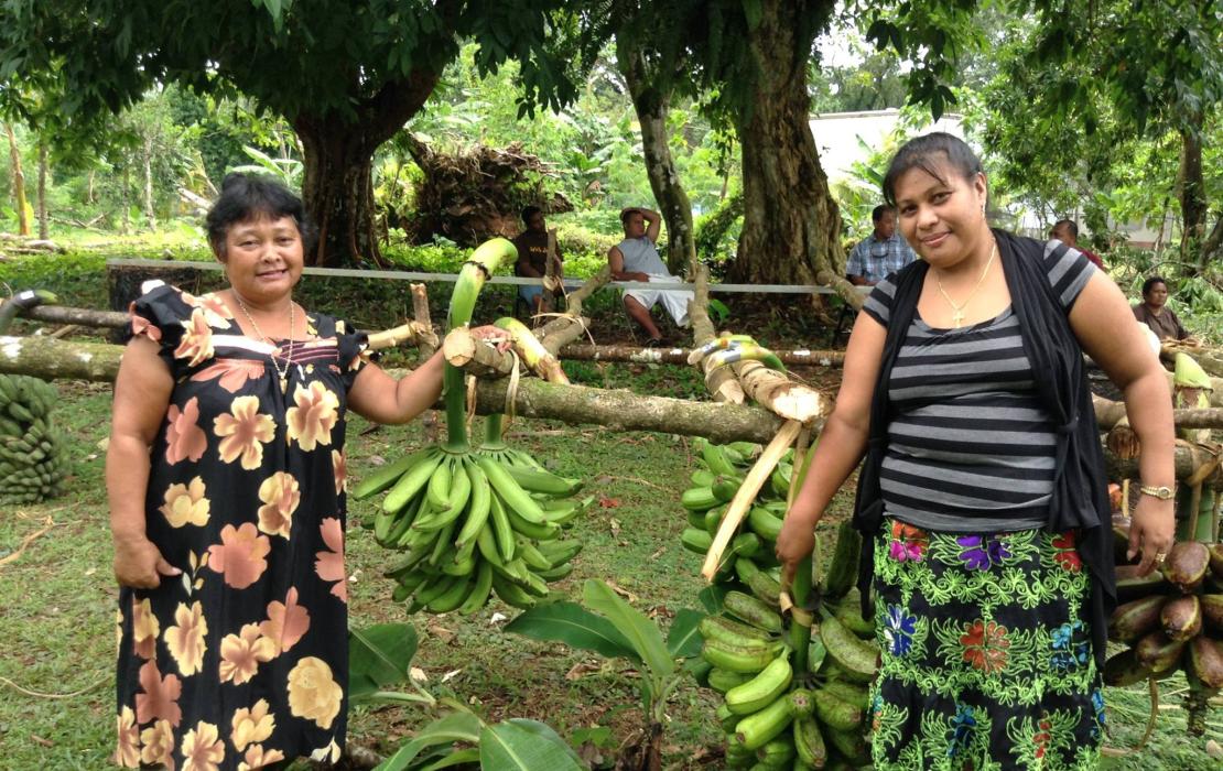 Two women from The Island Food Community of Pohnpei pose for a photo, holding locally harvested bananas.