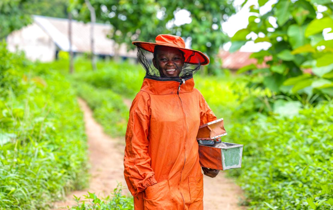 Une femme portant une combinaison de protection pour l'apiculture et la production de miel dans une ferme apicole au Kenya.