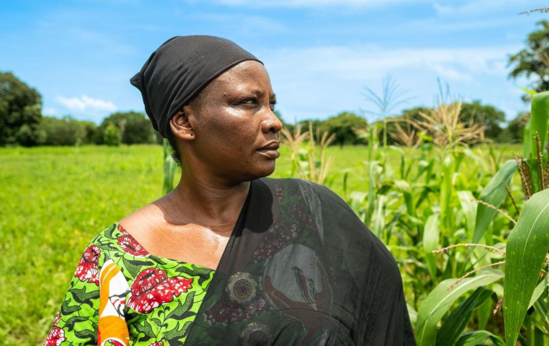 A woman standing in a field looking far away in Burkina Faso