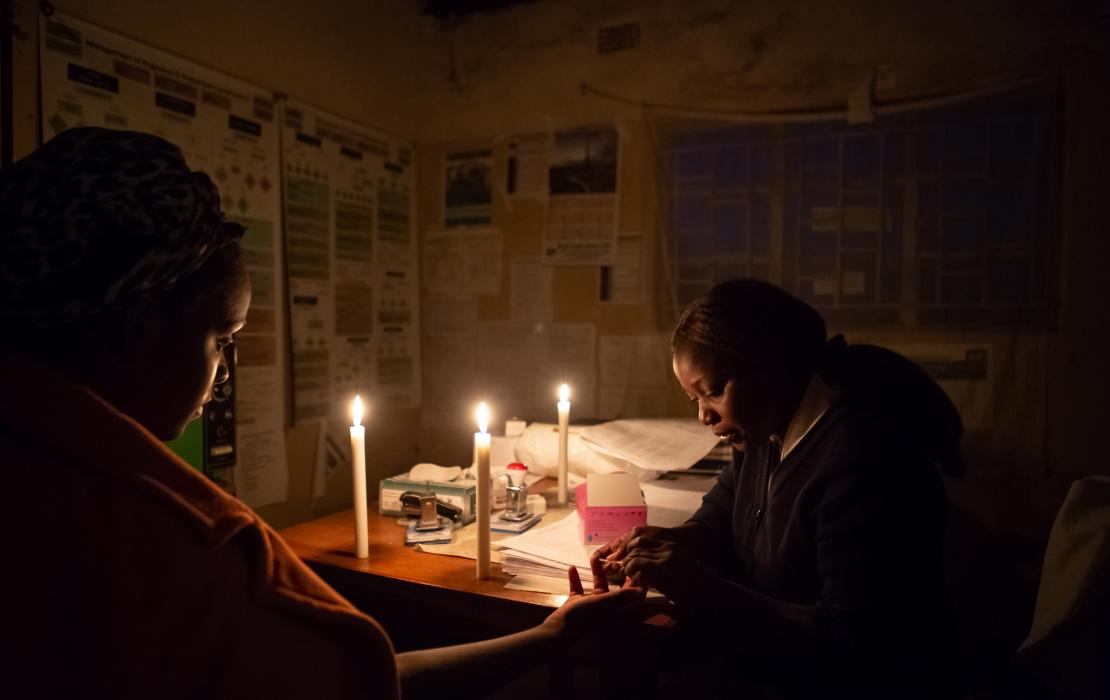 Two women using candles to work at night