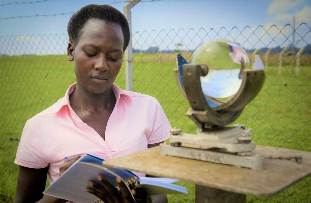 A woman writing notes in front of a transparent globe