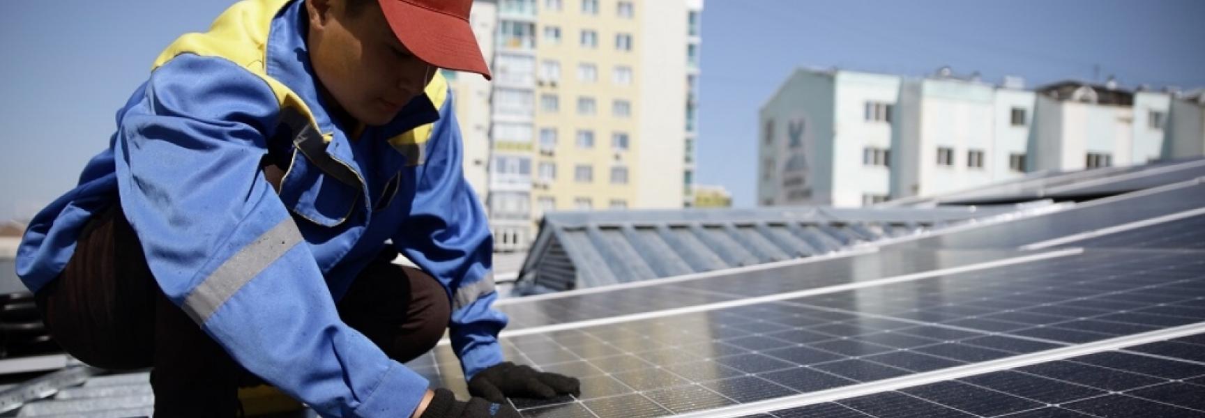 Hombre instala paneles solares en techos en Kazajistán