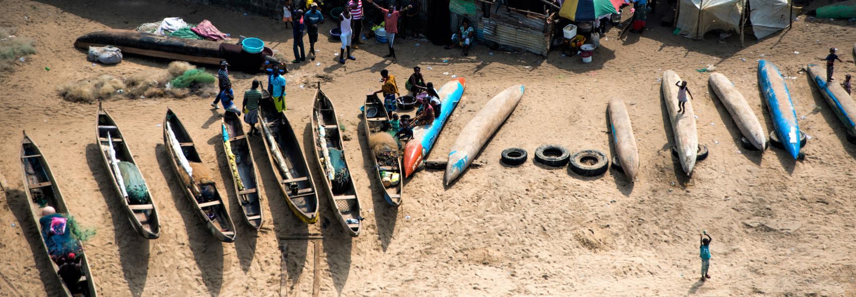 Pescadores y sus familias junto a botes en una playa en Liberia