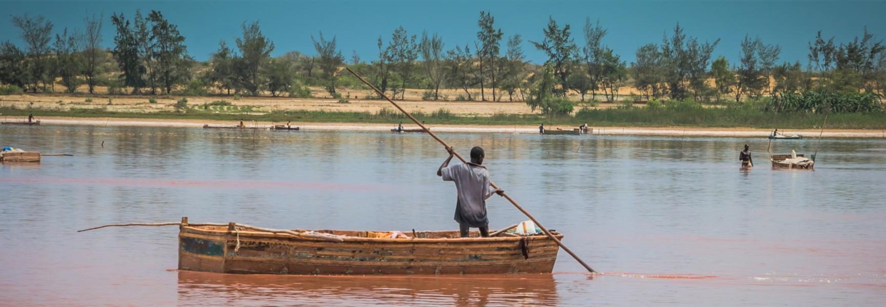 Un homme sur une barque récoltant du sel au Lac rose au Sénégal.