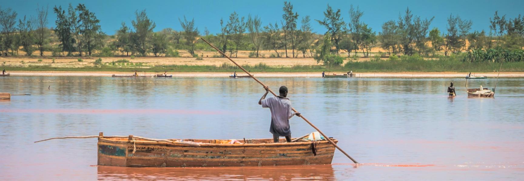 A man on a boat harvesting salt in the Pink Lake in Senegal