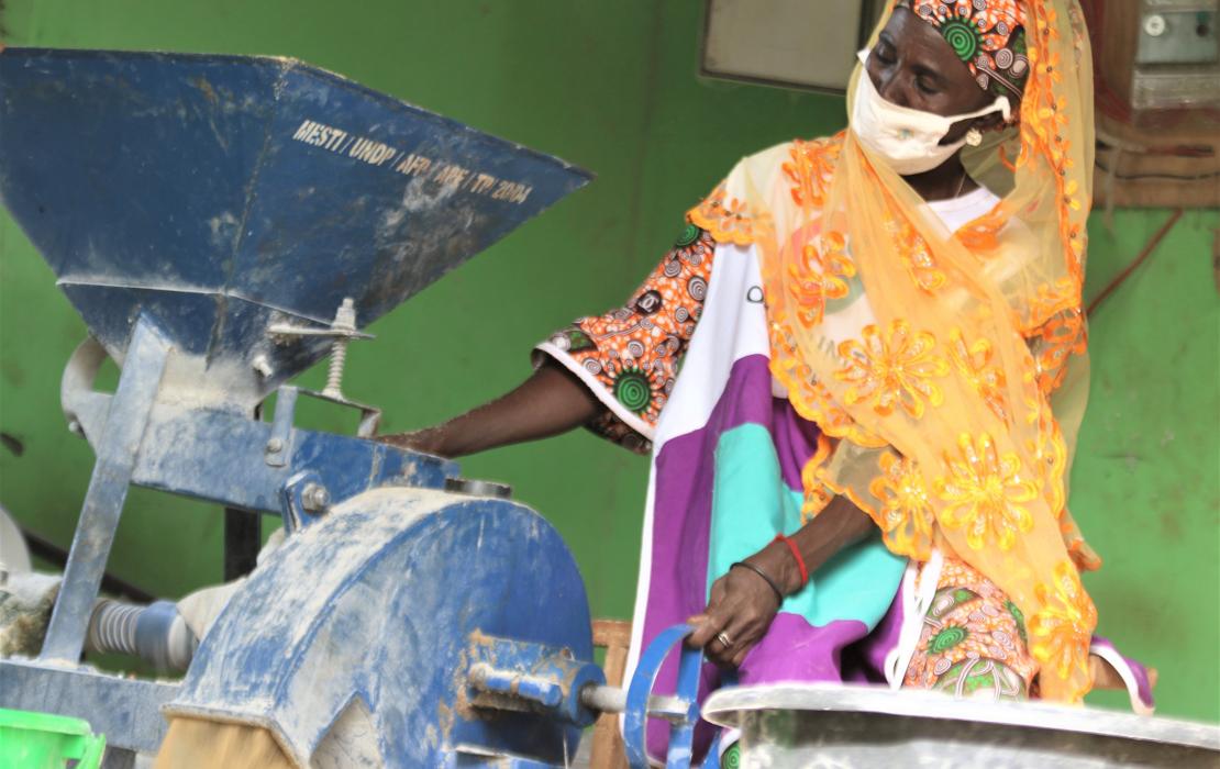 A woman farmer using a mill provided by UNDP in Tampion, Ghana