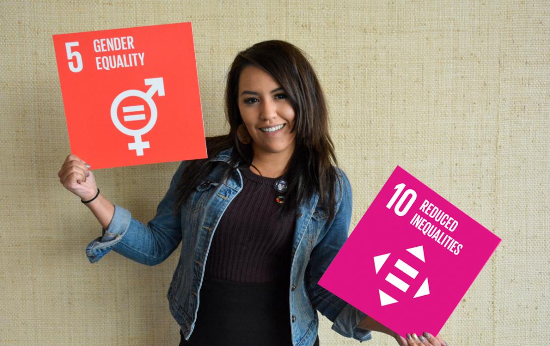 Woman holds signs with logo of SDG5 (Gender Equality) and SDG10 (Reduced Inequalities) on them.