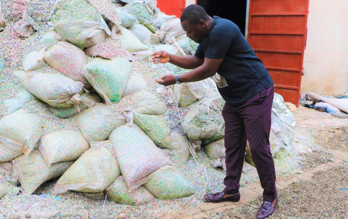 Entrepreneur Nelson Boateng, founder of Nelplast Ghana, inspecting the plastic pellets that will be transformed into bricks and pavement blocks and used as buidling materials.