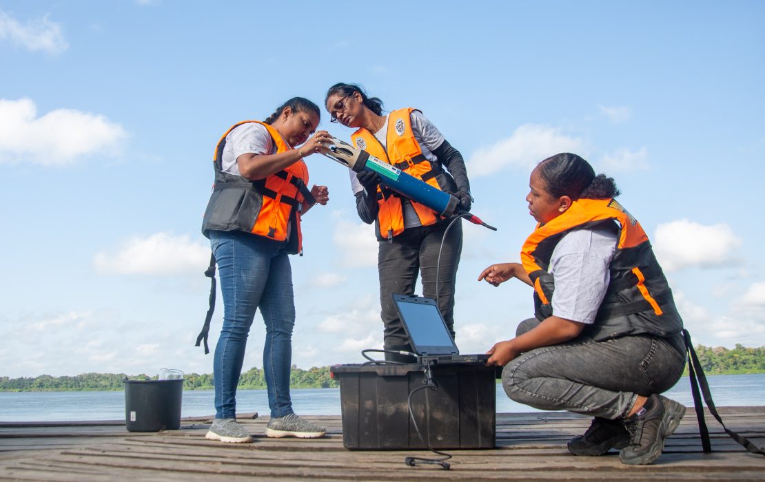 Mujeres realizan mediciones de la calidad del agua como parte de una iniciativa de capacitación de funcionarias para liderar la gestión medioambiental en Suriname