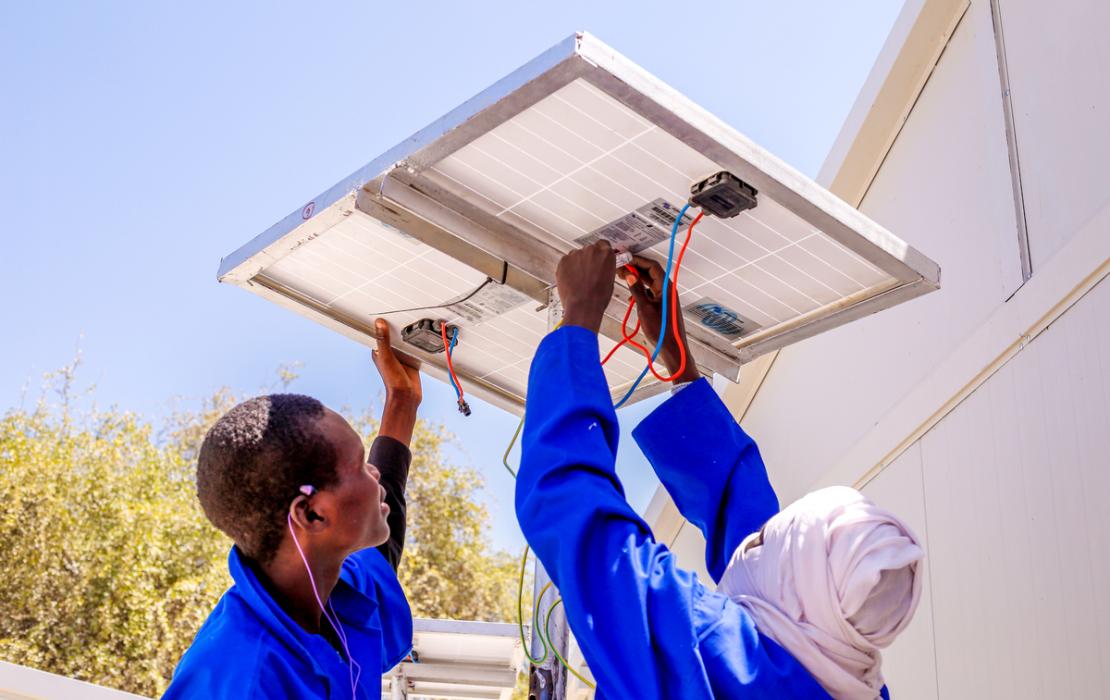 Deux hommes installent des panneaux solaires au Niger