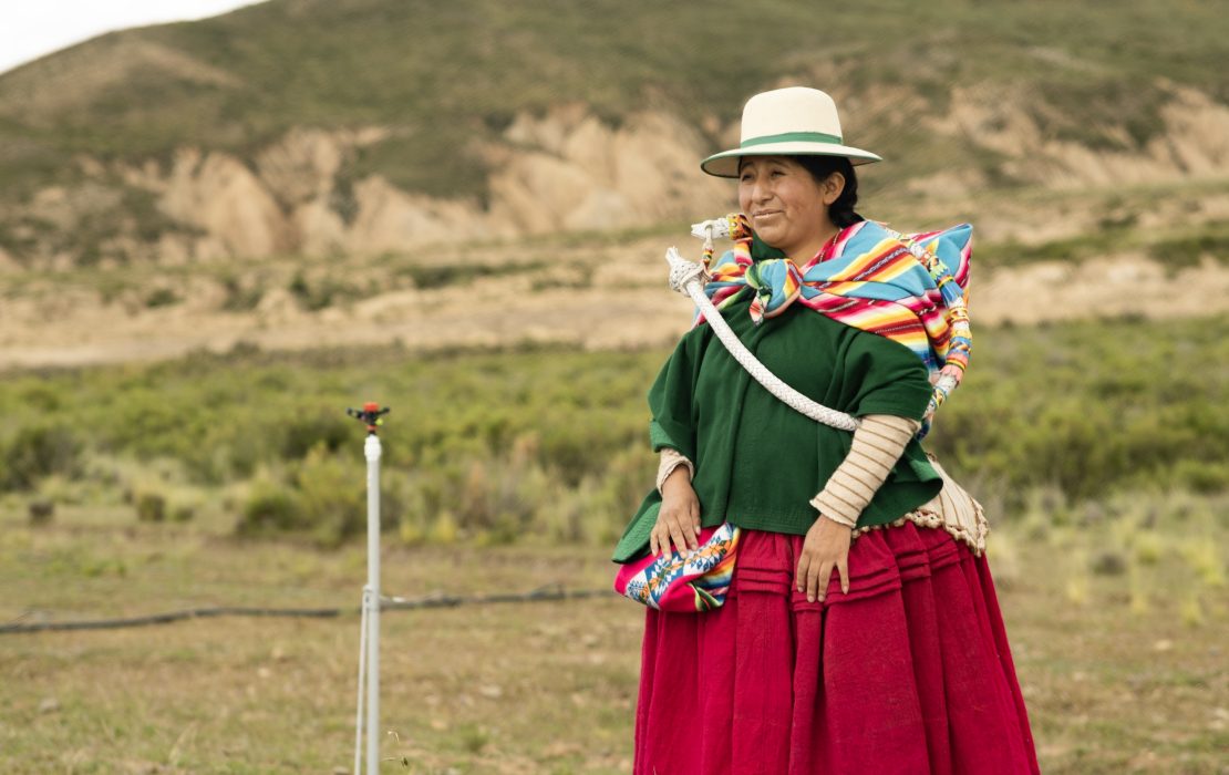 woman standing next to a water irrigation system in Santiago de Callapa, Bolivia