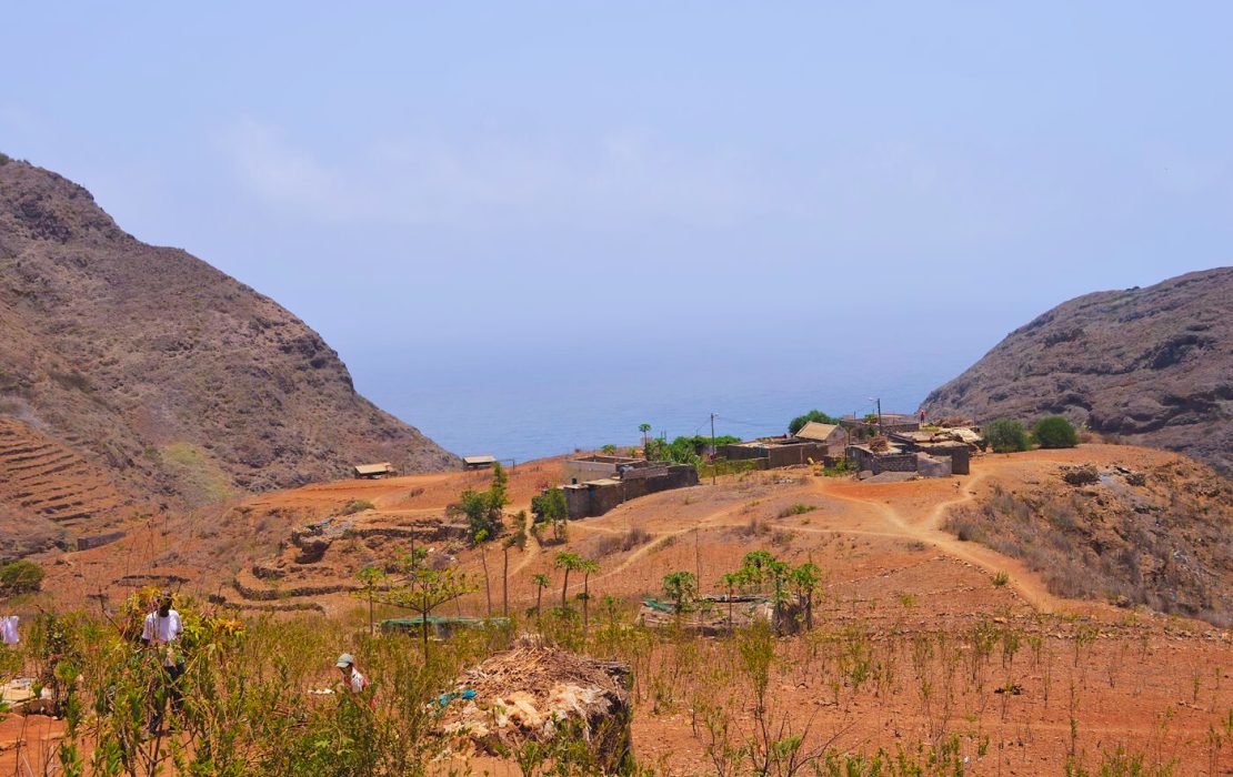 Un petit village rural entouré de collines arides, avec l’océan Atlantique en arrière-plan par une journée ensoleillée, au Cabo Verde