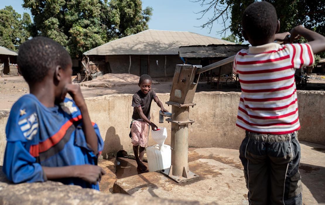 Children draw water from a well in a village in rural Guinea Bissau in Africa.