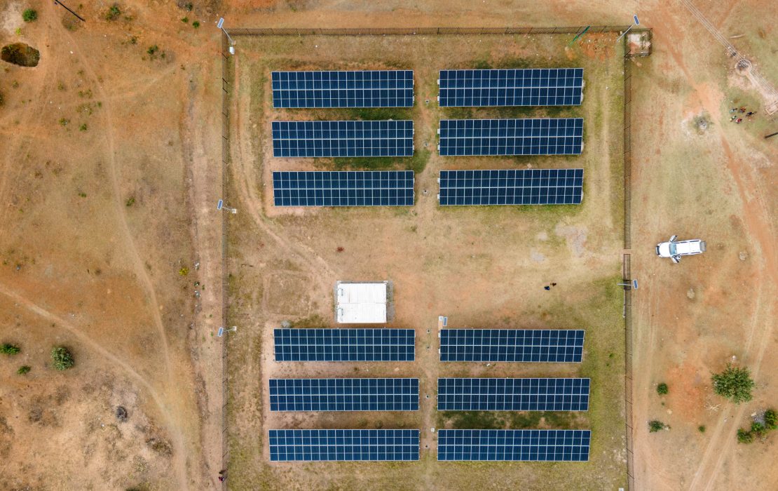 Sustainable energy is among the economic sectors prioritized in Zimbabwe’s Investment Framework. Photo: UNDP Zimbabwe Aerial view of a solar farm featuring neatly aligned rows of solar panels in a rectangular grid surrounded by dry terrain with sparse vegetation in Zimbabwe.