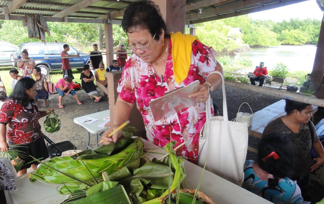 A woman inspects handicrafts including a basket made using locally harvested crops. 