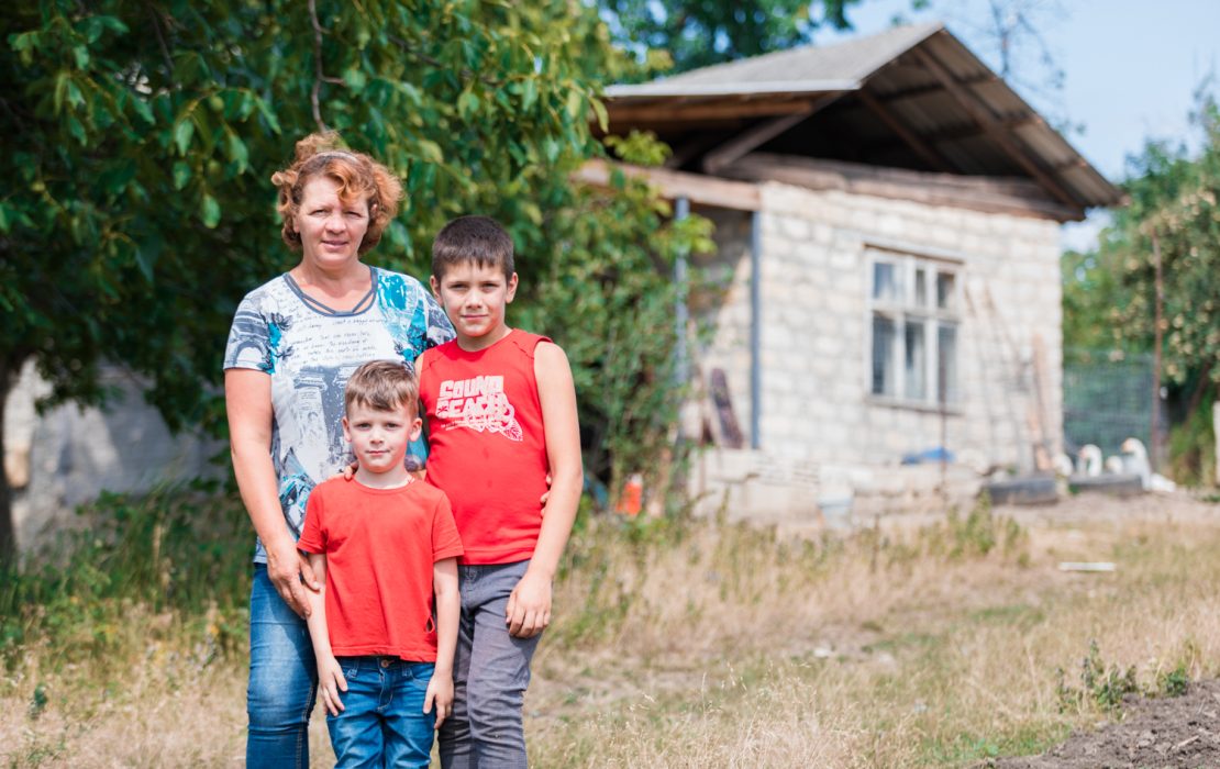 With sustainable energy, Maria made her family business more profitable and ready for her children to expand in the future. Photo: UNDP Moldova A woman and her two sons standing in front of their house in rural Moldova