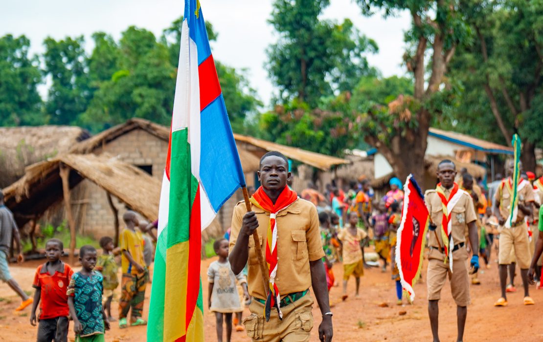 Des jeunes marchant dans une rue en portant le drapeau national en République centrafricaine
