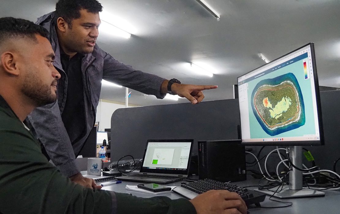 Two government officers look at modelling on a computer screen.