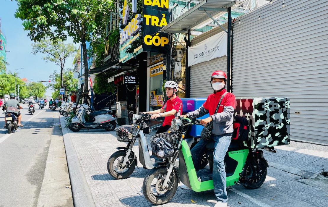 Two shippers riding their e-motorikes in a street in the city of Hue, Viet Nam