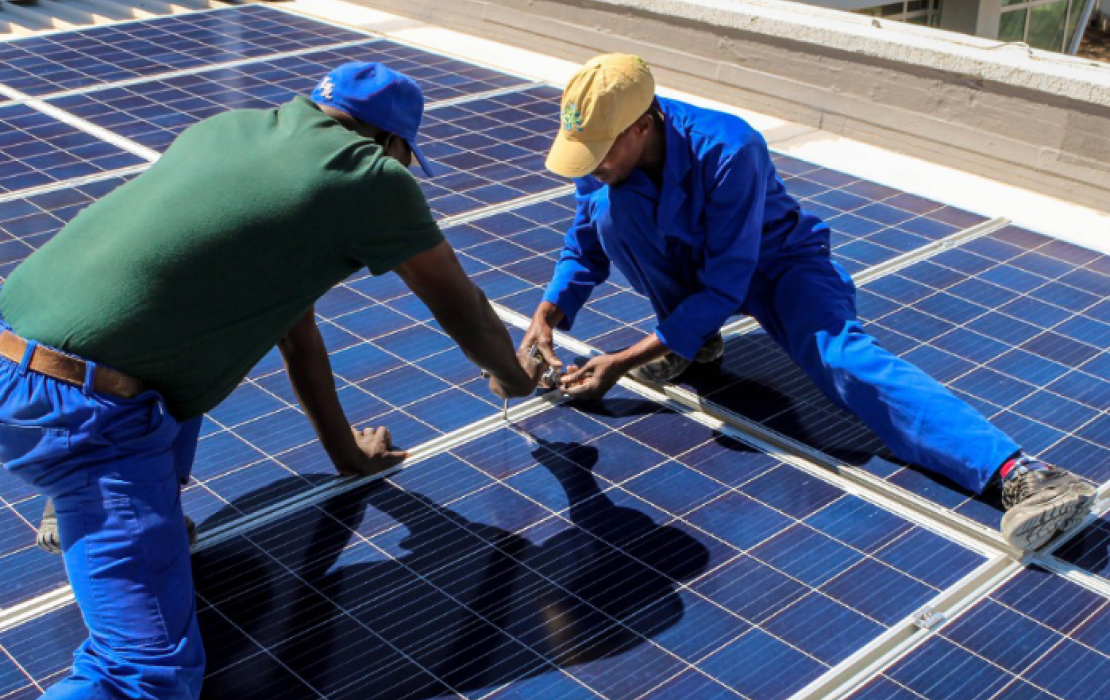 Two installing solar panels on a roof in Ghana