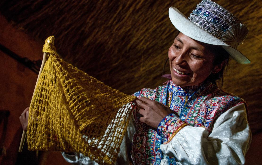 Ruth Cutipa de la comunidad Sibayo en Peru sostiene una pieza que tejió utilizando una máquina impulsada por energía solar..
