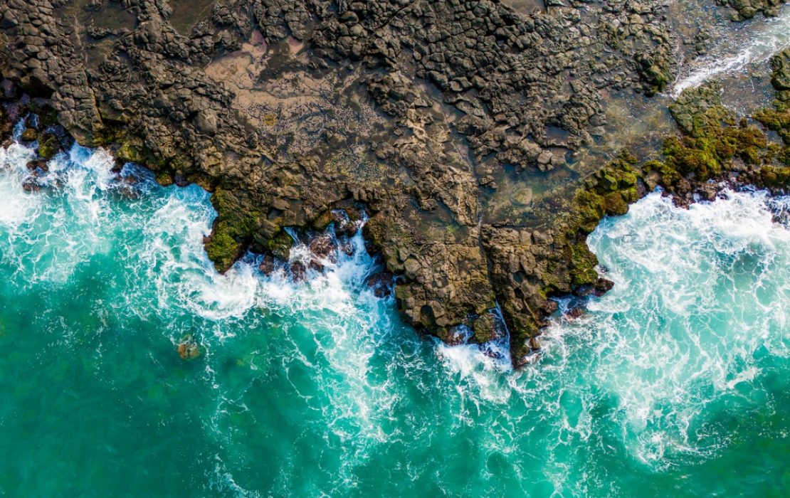 Senegal is located at the westernmost point of Africa, along the Atlantic ocean coast. Photo: Ugochukwu Kingsley Ahuchaogu / UNDP WACA Aerial view of ocean waves crashing against a rugged rocky shoreline, showing the dynamic interaction between land and sea and the power of coastal ecosystems in Senegal.