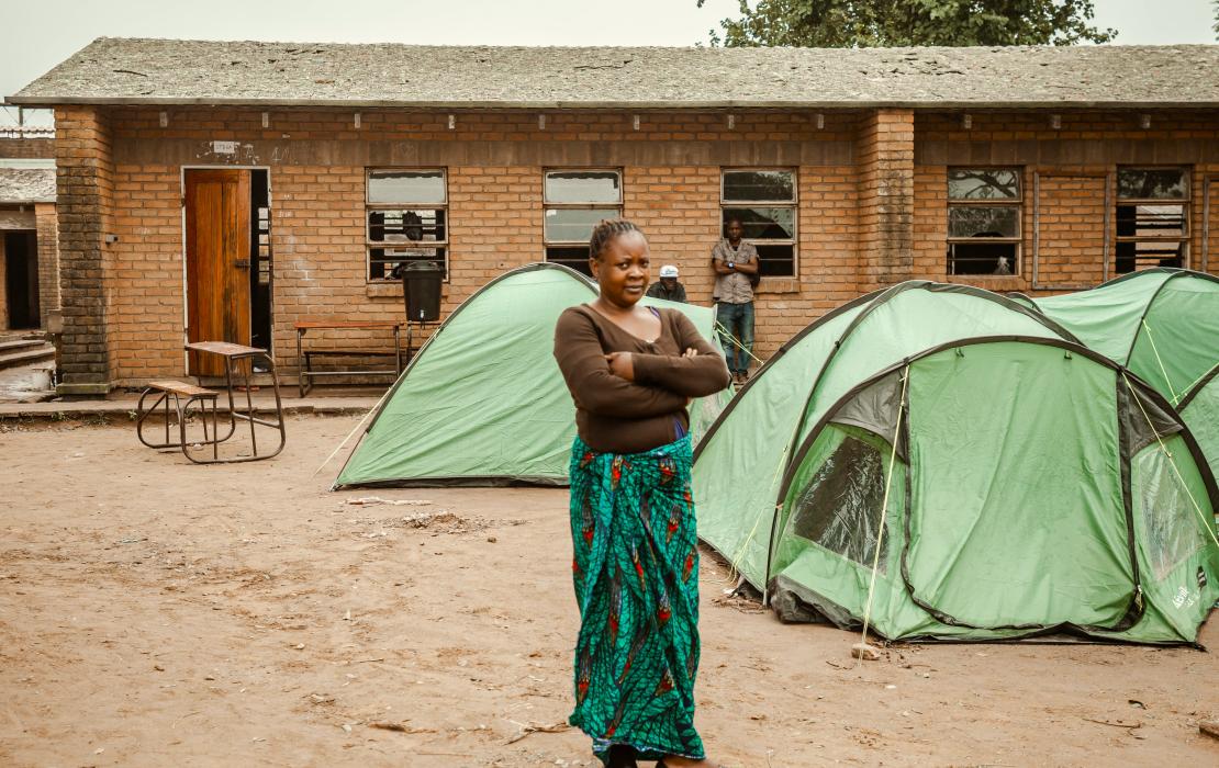 A woman standing near tents at the evacuation camp set up in Manja Primary School in Blantyre