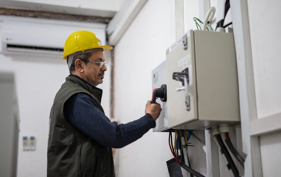 Engineer at UNDP Yemen checking power capacity of solar energy system.