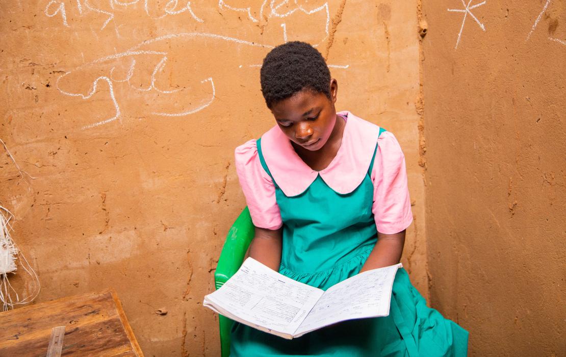 A schoolgirl reading her school notebook at home in Malawi
