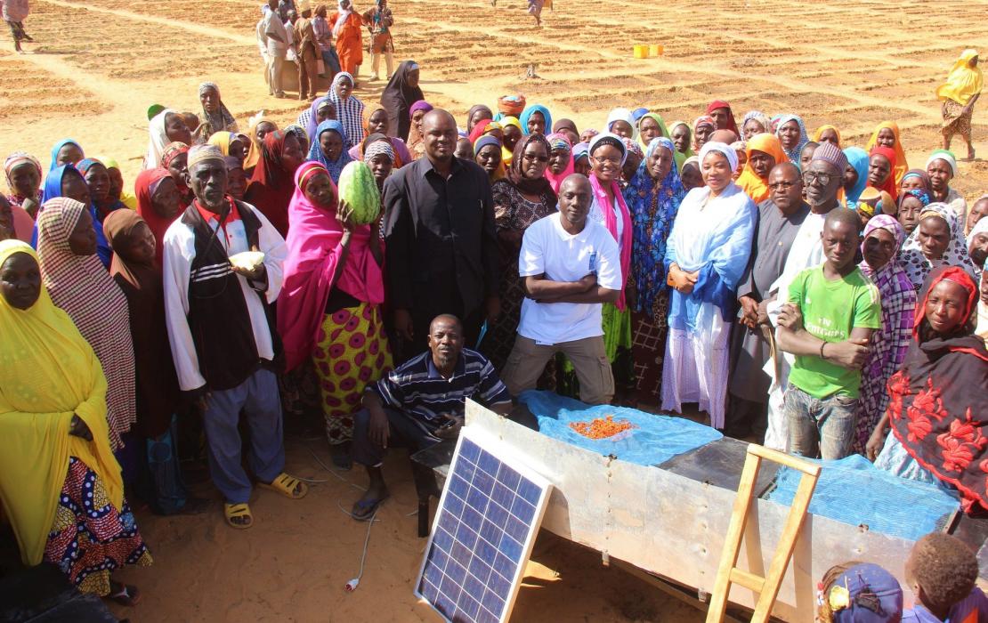 Des villageois rassemblés autour de panneaux solaires près de leurs champs au Niger.