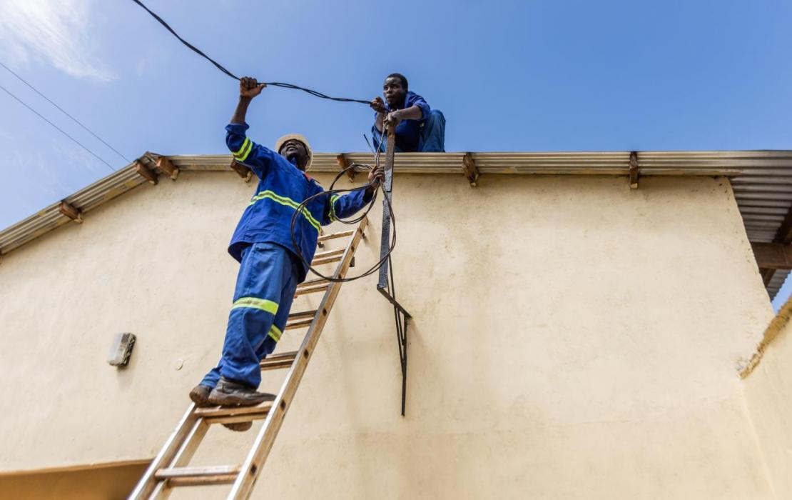 Two men installing a solar energy installation in Malawi.