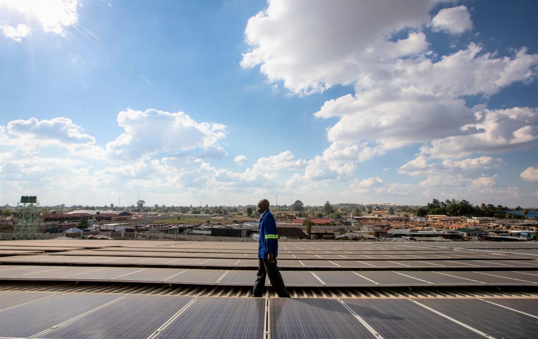 A technician walking on a roof installed with solar panels in Africa
