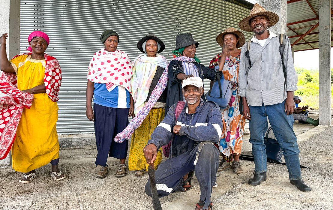 A group of smiling community members in Comoros stands in front of a water tank.