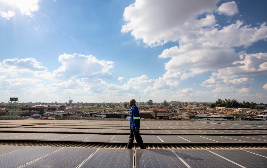 A technician walking on a roof installed with solar panels in Africa