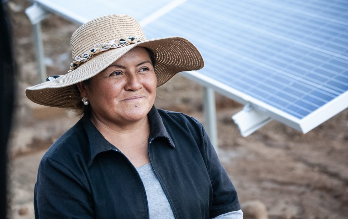 Mujer junto a un panel solar en Bolivia