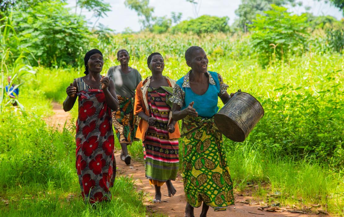 A group of women walking and singing in a field in Malawi