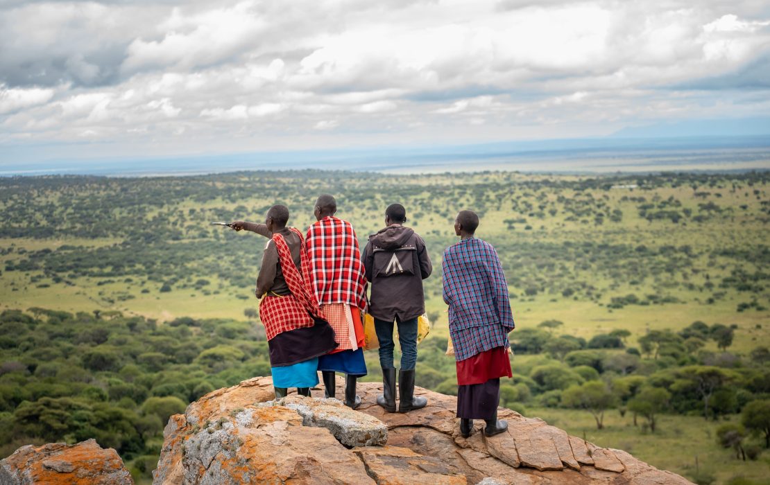 Cuatro personas de pie sobre una roca en la montaña observan el paisaje en Tanzania.