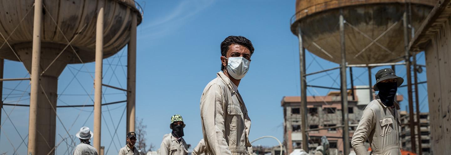 Men stand by two towers in Mosul, Iraq