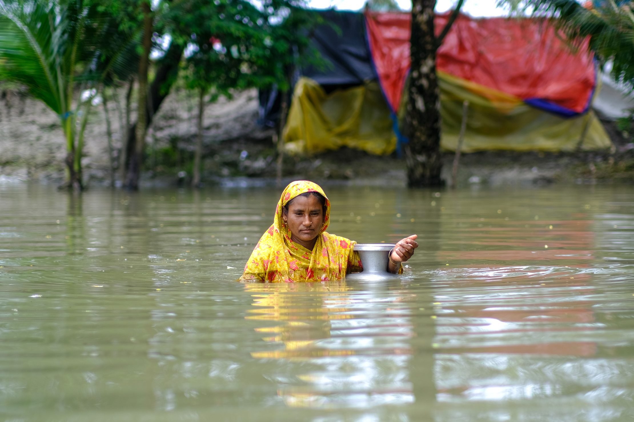 Climate change tends to magnify existing divides in society, with women and men experiencing its impacts in different and unequal ways. Photo: UNDP Bangladesh A woman wades through floodwaters in coastal Bangladesh.