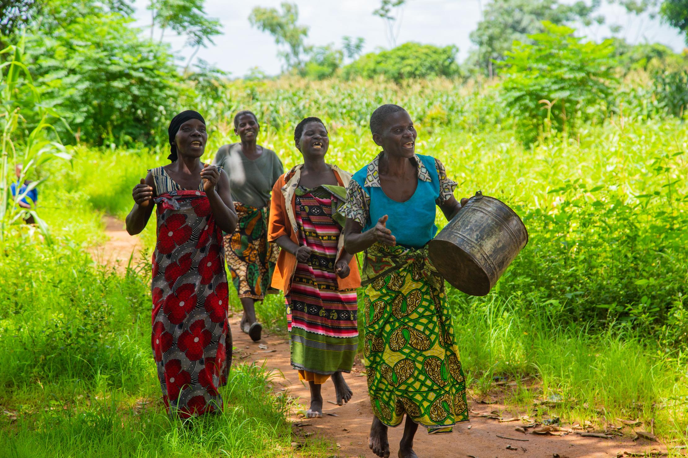 A group of women walking and singing in a field in Malawi