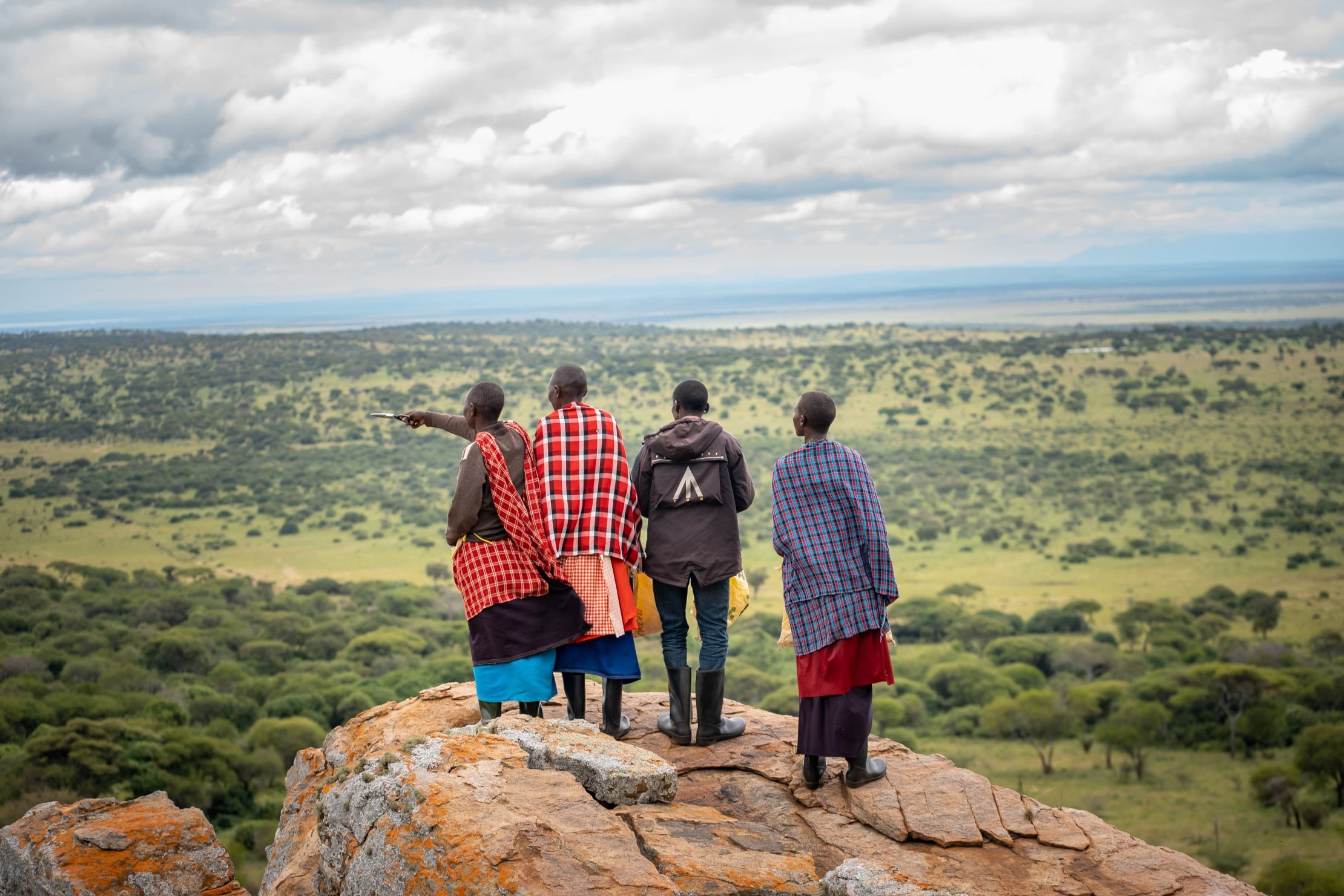 Cuatro personas de pie sobre una roca en la montaña observan el paisaje en Tanzania.