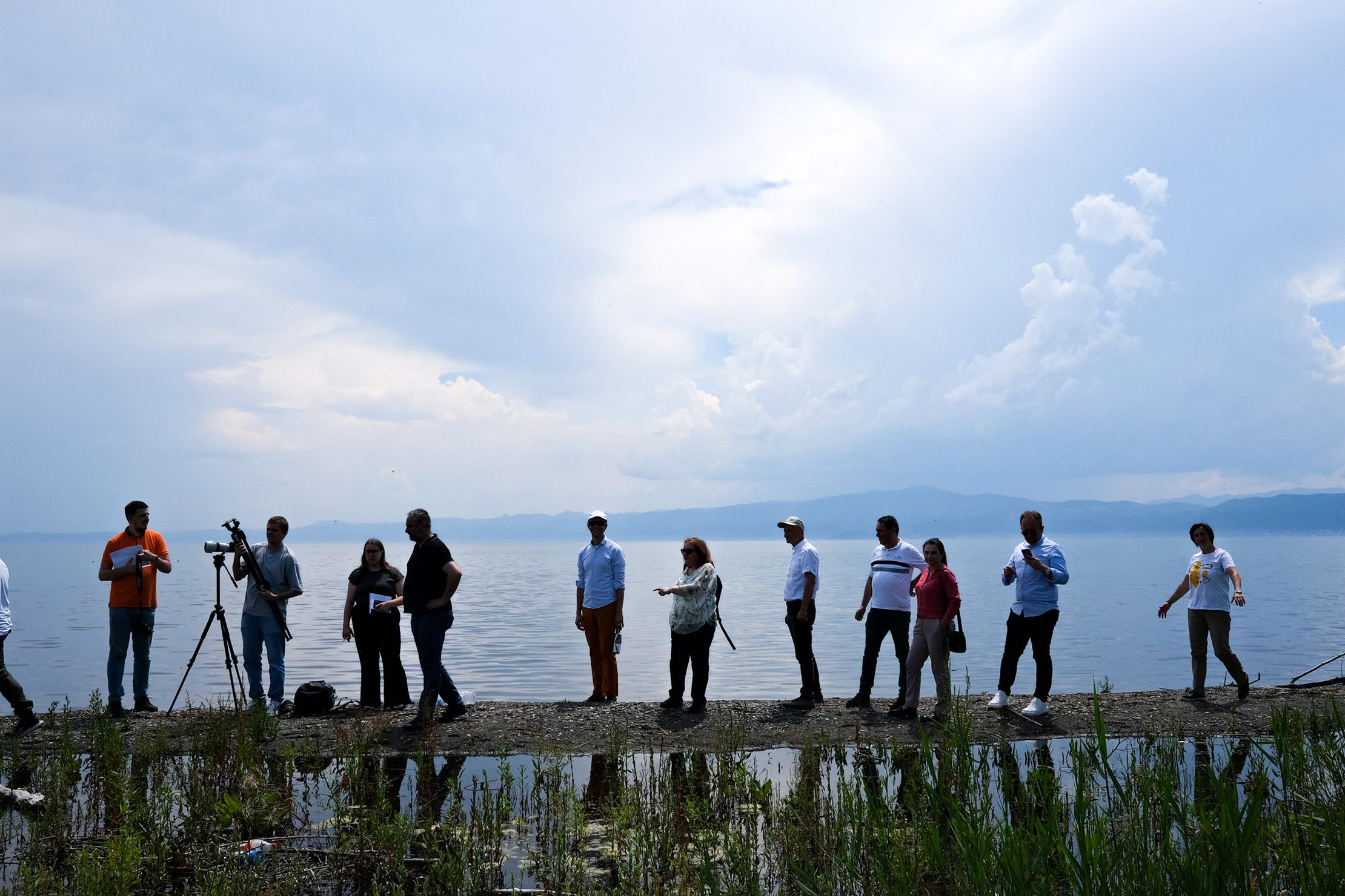 When it comes to climate change impacts such as flooding, it’s clear no country can face them alone. Photo: UNDP A group of people, including UNDP and Adaptation Fund representatives, stand along the shore of a lake in North Macedonia during a project visit, with mountains visible in the distance.