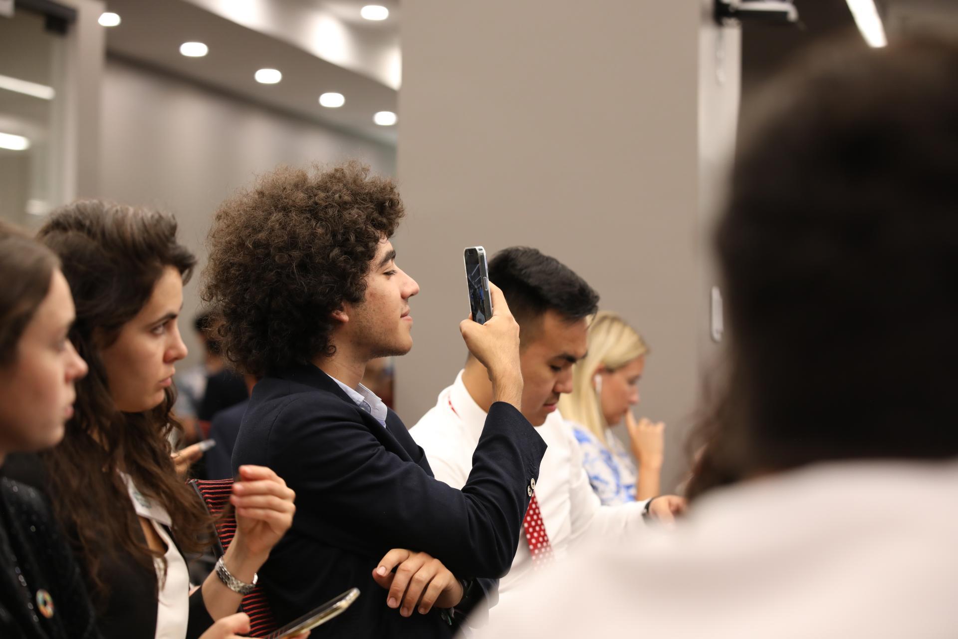 Omar (centre) photographs a meeting at the Youth4Climate: Powering Action event at the United Nations General Assembly.