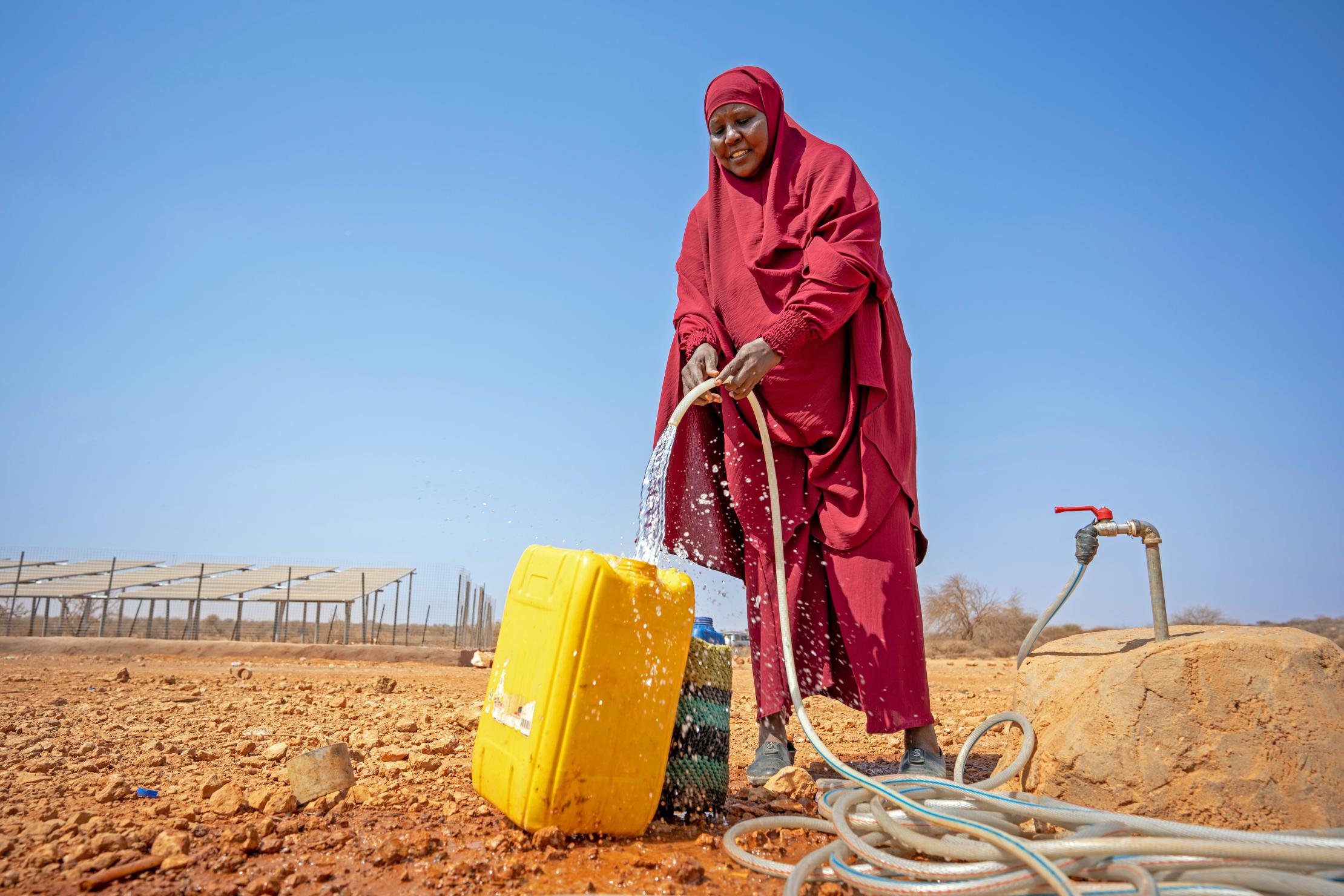 Mujer en Somalia recolectando agua de una estación que funciona a base de energía solar