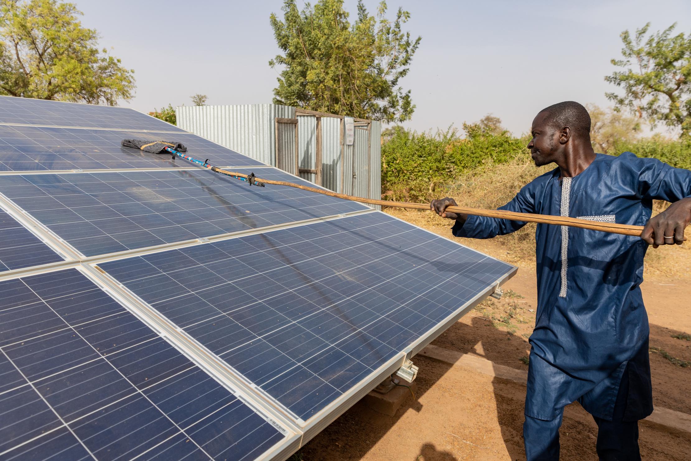 Un homme entretenant un panneau solaire au Mali.