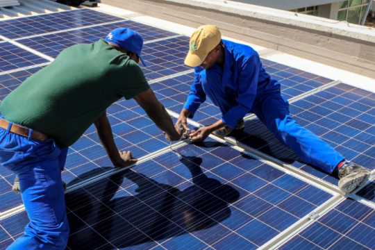 Two men installing solar panels in Ghana