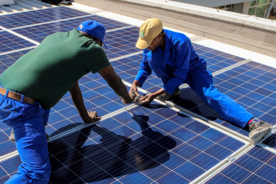 Two men installing solar panels in Ghana. Photo : UNDP Ghana Two men installing solar panels in Ghana