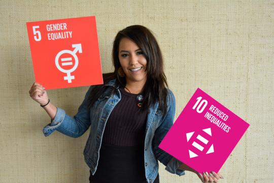 Woman holds signs with logo of SDG5 (Gender Equality) and SDG10 (Reduced Inequalities) on them.