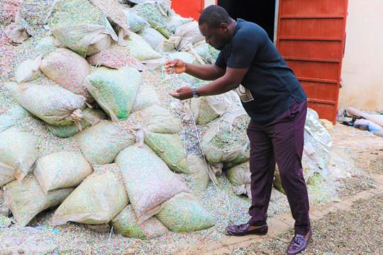 Entrepreneur Nelson Boateng, founder of Nelplast Ghana, inspecting the plastic pellets that will be transformed into bricks and pavement blocks and used as buidling materials.